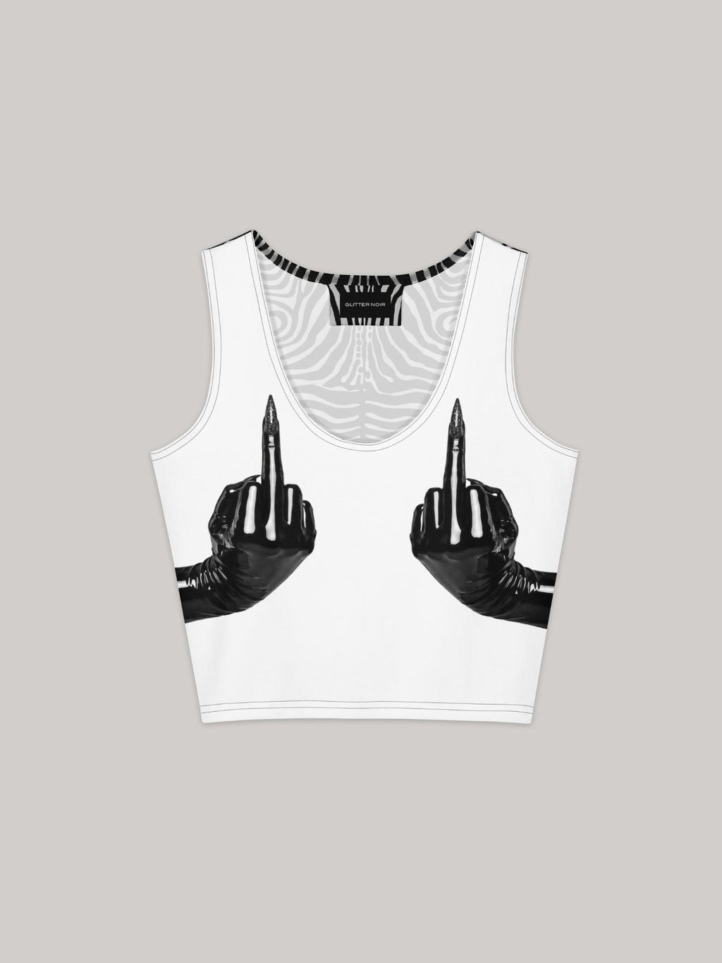 White sleeveless crop top with all-over print graphic featuring two black latex-gloved hands extending middle fingers with pointed stiletto nails, positioned at chest level. Black and white swirling zebra-pattern lining visible at neckline and armhole trim. Glitter Noir branded label at interior neckline. Ghost flat lay on white background.