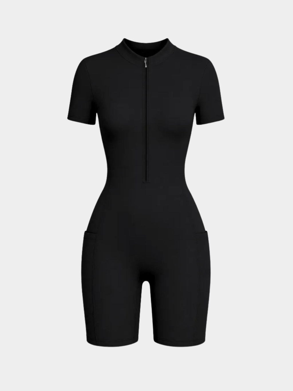 Black short-sleeve zip-front romper styled on a model with white socks and black strappy heels against a light gray studio background.