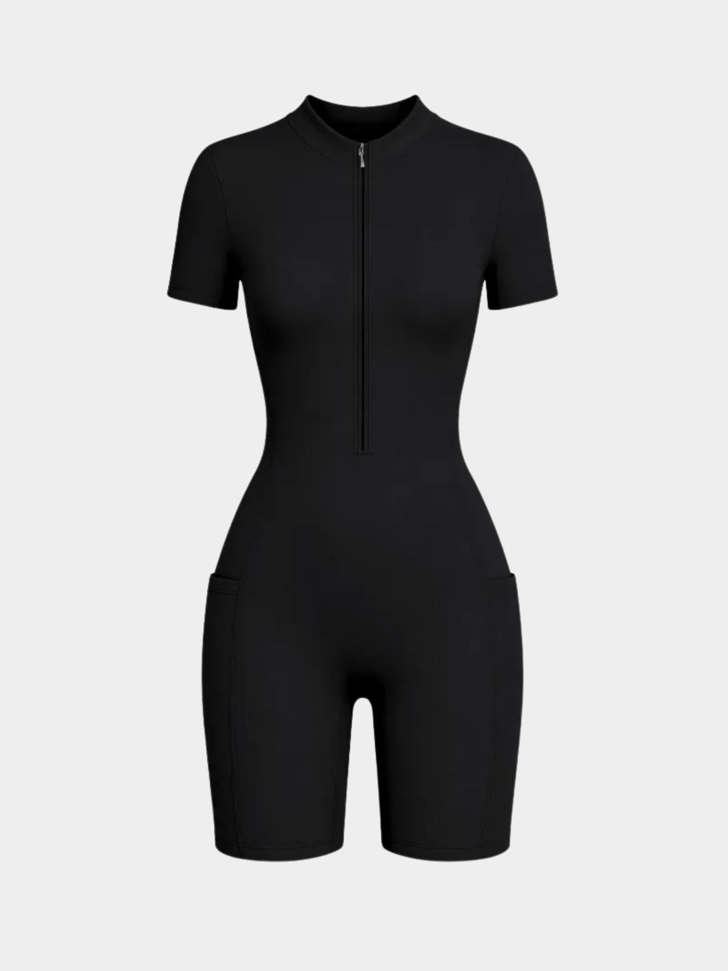 Black short-sleeve zip-front romper styled on a model with white socks and black strappy heels against a light gray studio background.